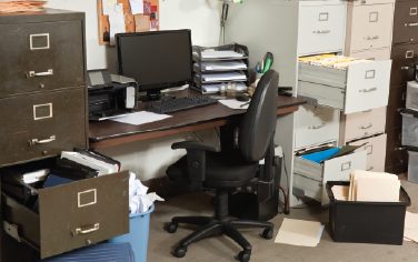 A disorganized office overflowing filing cabinets