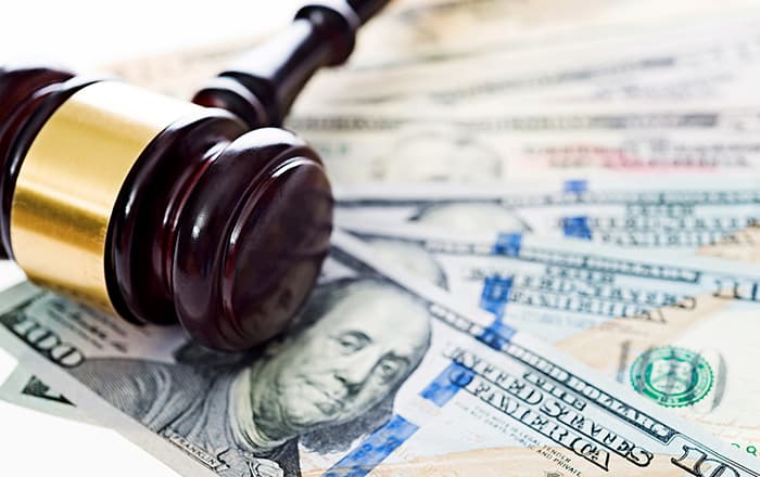 A gavel laying atop several $100 bills