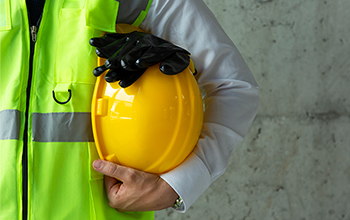 Worker holding a hard hat and rubber gloves