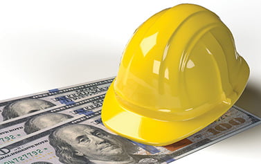 Yellow hard hat on top of US dollar bills