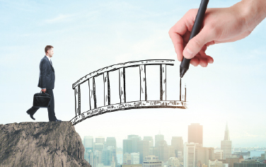 A businessman about to walk across an illustrated bridge being drawn by a hand
