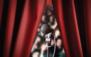 Microphone in front of an audience and a red curtain